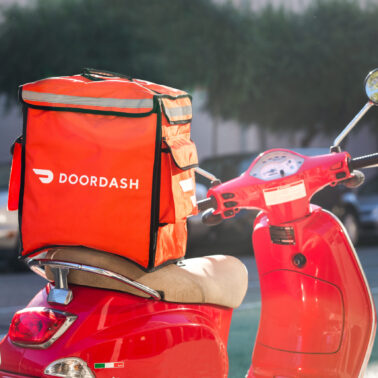 Red DoorDash bag sitting on the back of a red scooter