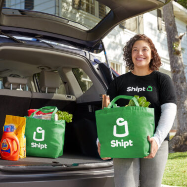Shipt shopper putting green Shipt shopping bags in the trunk of a car