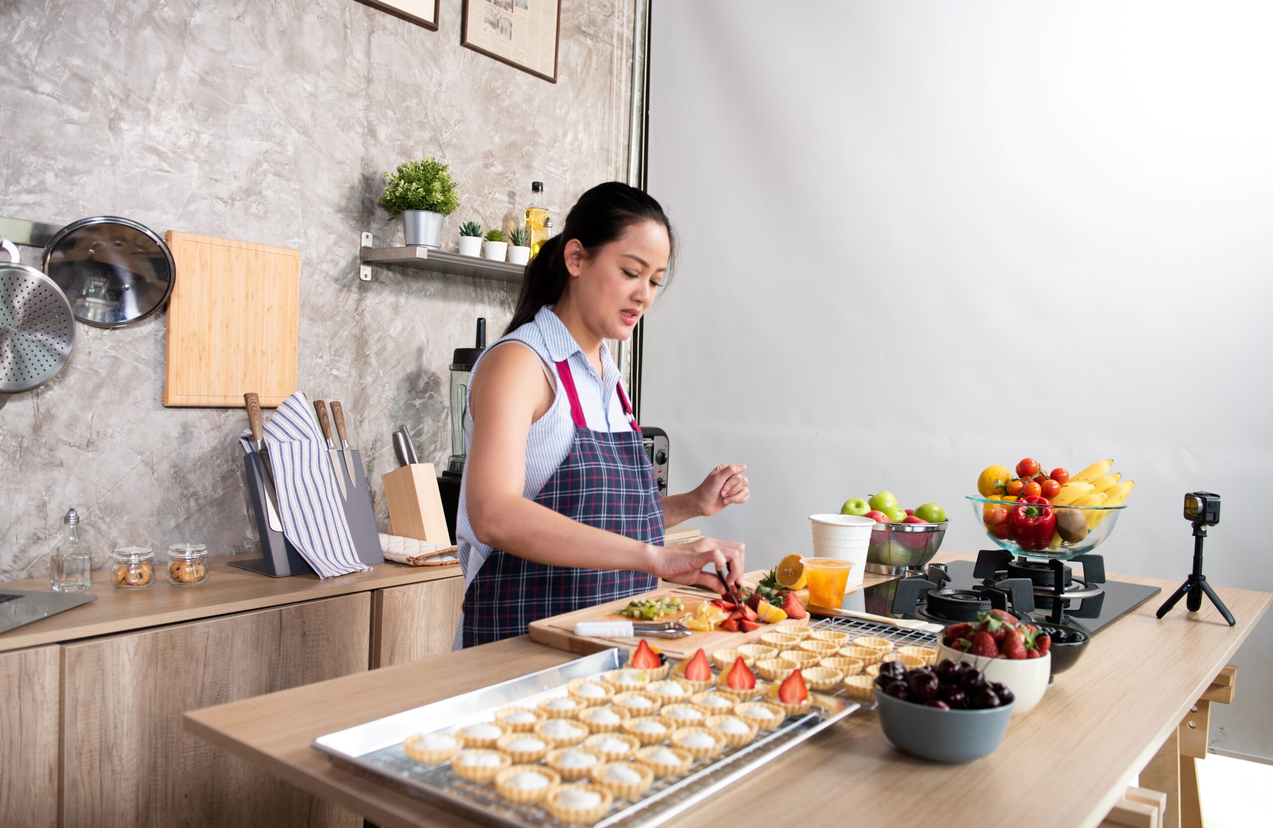 Woman making fruit tarts in a kitchen