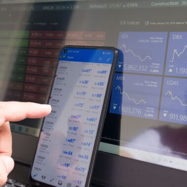 black phone showing stock market analysis in front of laptop