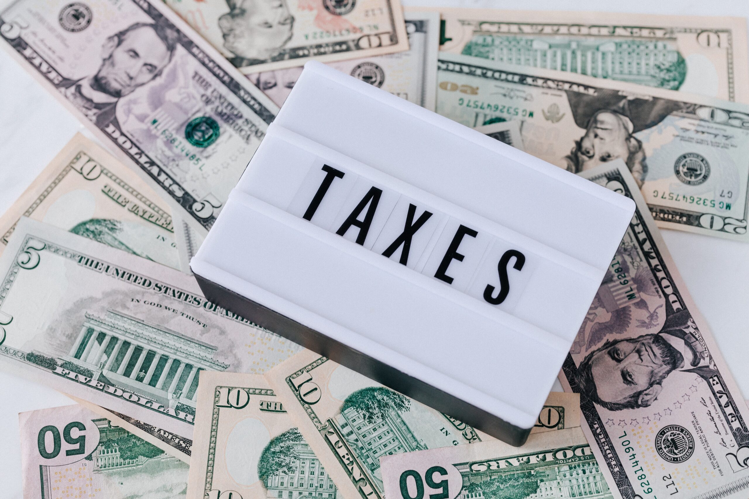 sign saying taxes laying on pile of cash
