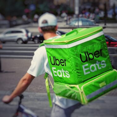 Uber Eats courier on a bike carrying a large green Uber Eats backpack